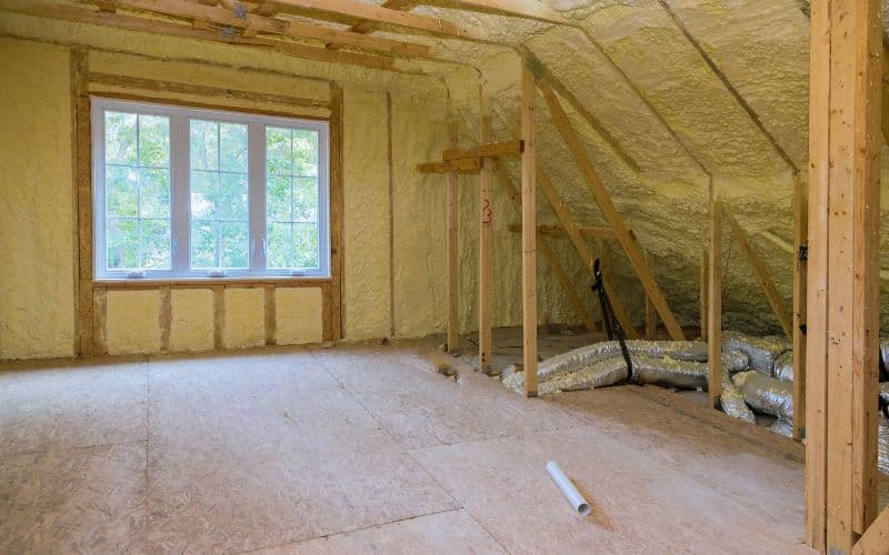 A house under construction viewed from inside a room insulated with spray foam.