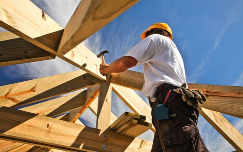 A builder working on the wooden frame for a straw bale home.