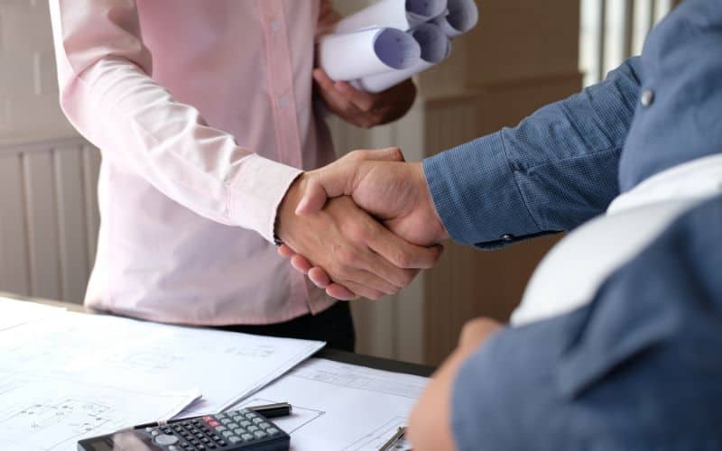 A contractor and client shaking hands over an agreement.