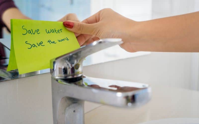 A water-saving tap with a post-it note saying "save water, save the world."