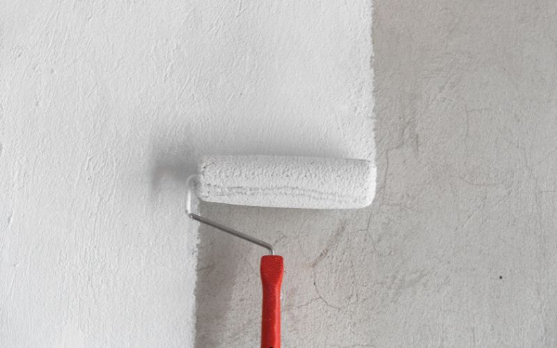 A straw bale wall being painted to preserve its looks and help to prevent moisture ingress.