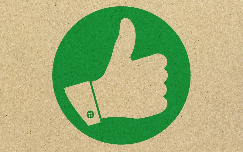 A green circle on a brown background with a brown thumbs up in the middle.