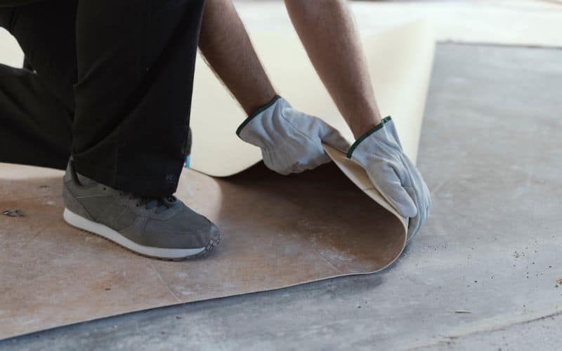 Linoleum flooring being lain on a concrete floor.