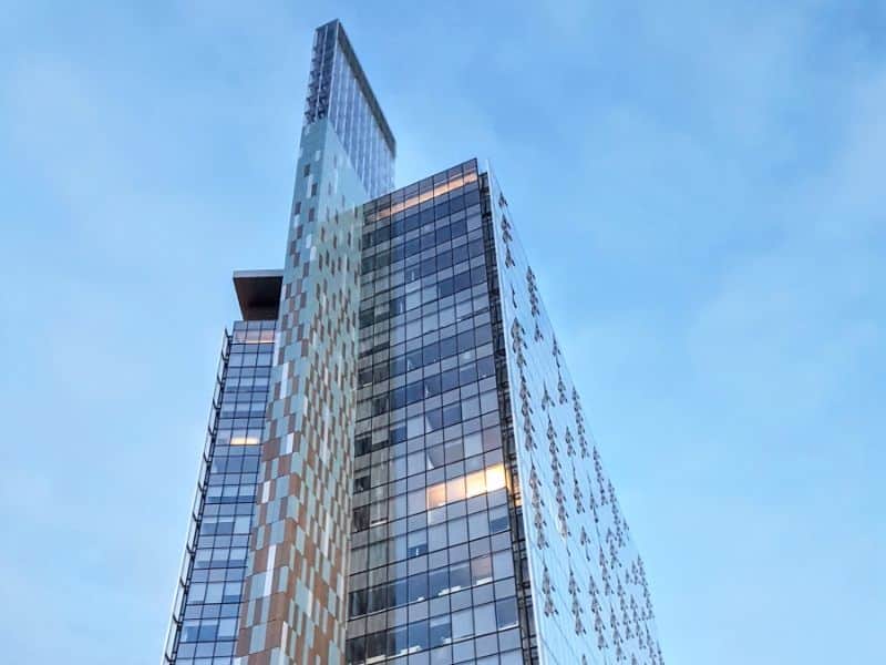 An image of Manitoba Hydro Place in Winnipeg, Canada. The building is a high-rise glass exterior building. It has an interesting feature that gives the appearance of a thin section being inserted into the main building.