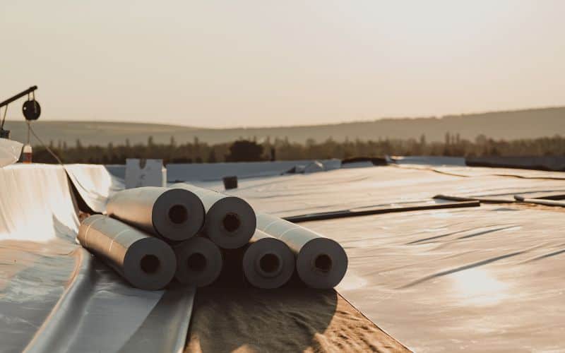 A rooftop with stacked rolls of rubberized membrane ready for installation.