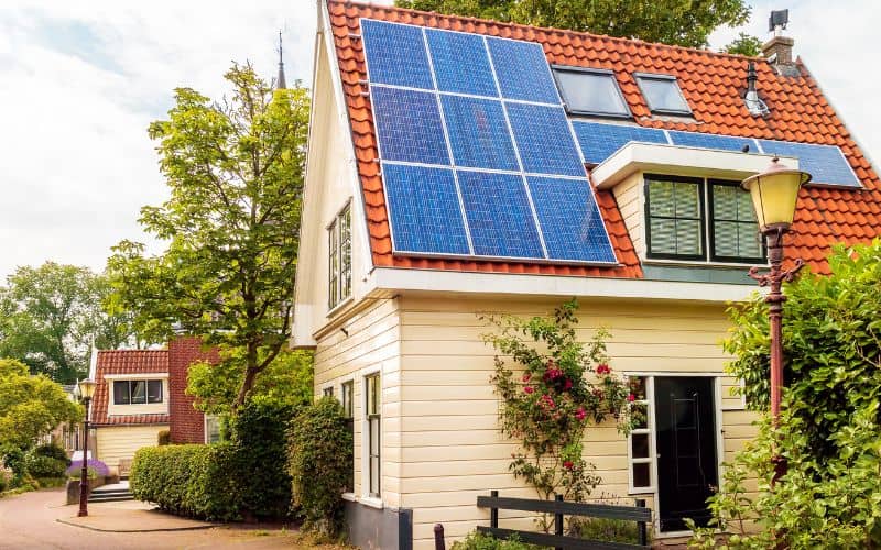 A house with an orange-tiled roof and solar panels. There are also velux roof lights and a dormer window in the roof.