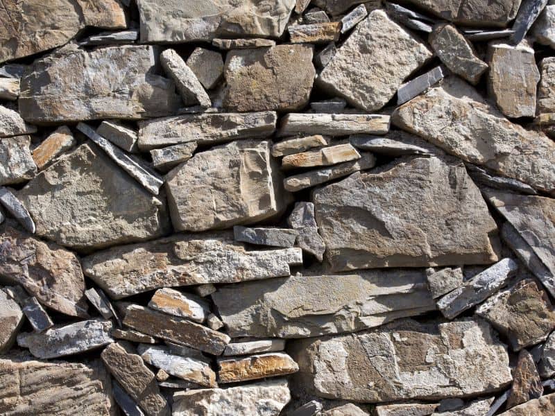 A stone wall with different sized pieces of stone arranged in an irregular pattern.