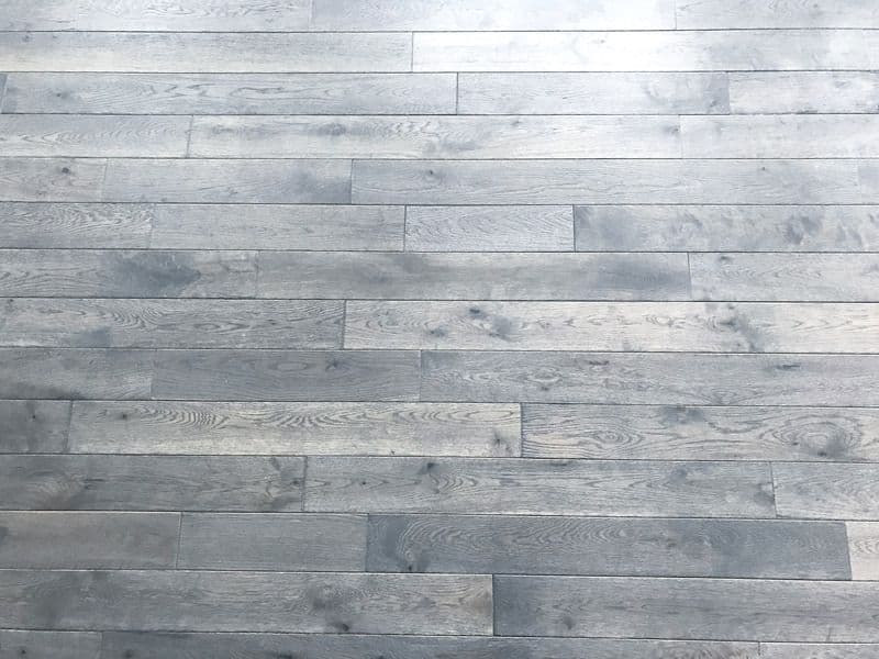 An unfinished hardwood floor in good condition with bright light reflecting back along the top edge.