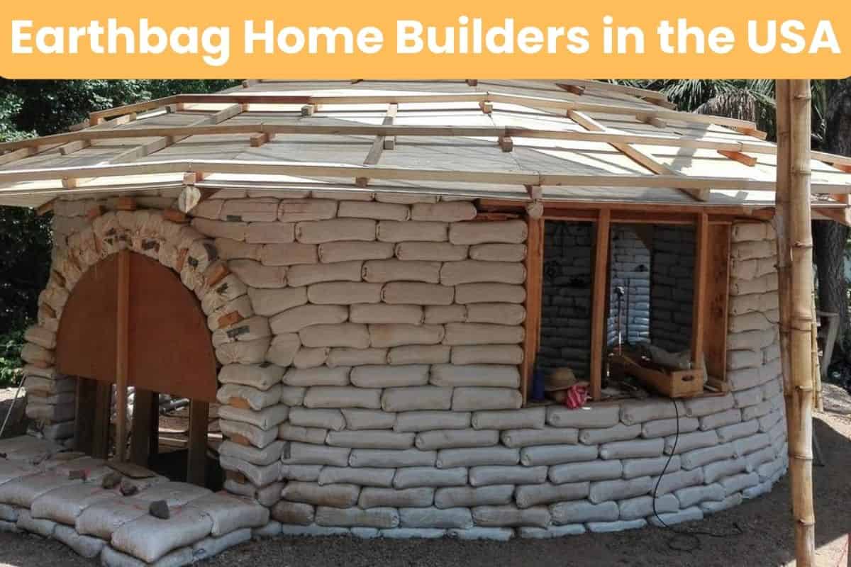 A round earthbag house under construction so the earthbags can still be seen. The structural elements of the roof have also been put up and there are holes for an entrance and a window. Across the top of the image are the words "Earthbag Home Builders in the USA."