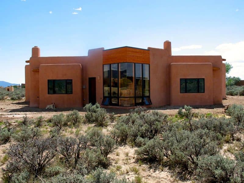 A photograph of the
Atrium House, built by the Salamander Company. Is have dark orange walls and large tinted windows. The house is set in arid scrubland.