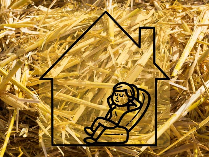 A photograph of straw fibers with a cartoon house with a person reclining in a comfortable chair inside.