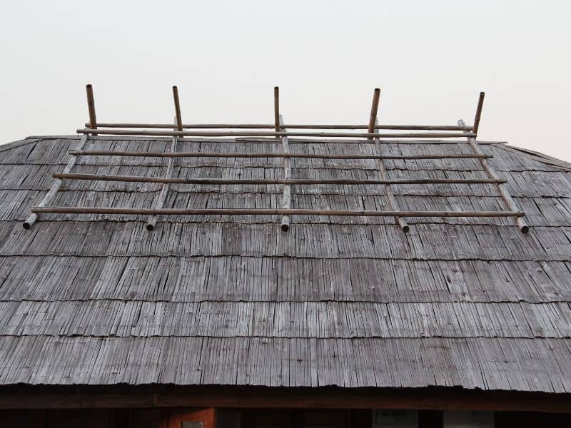 A flattened bamboo roof  with each row of strips overlapping the one below. There is a flat frame laid across the ridge.