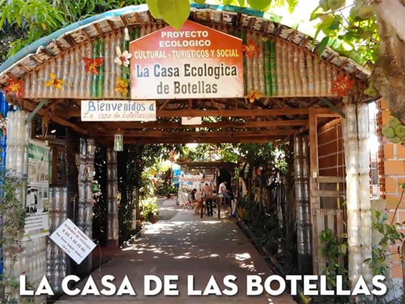 La Casa de Botellas built by Alfredo Santa Cruz in Puerto Iguazu, Argentina. The structure is built from all kinds of plastics, including CD jewel cases for the windows. The image shows the entrance, which has a curved roof and facade that clearly shows the plastic bottles used in its construction.