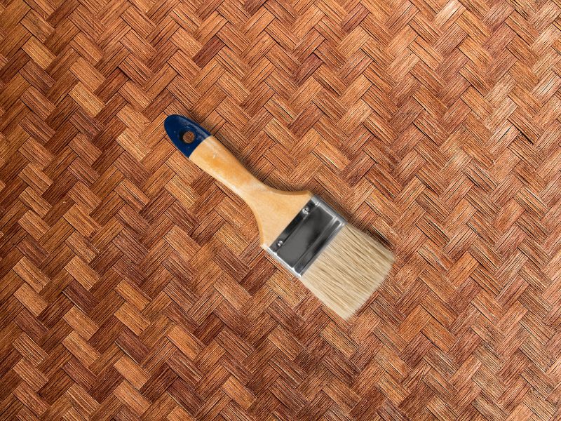 A woven sheet of bamboo roofing material with a paintbrush on it.