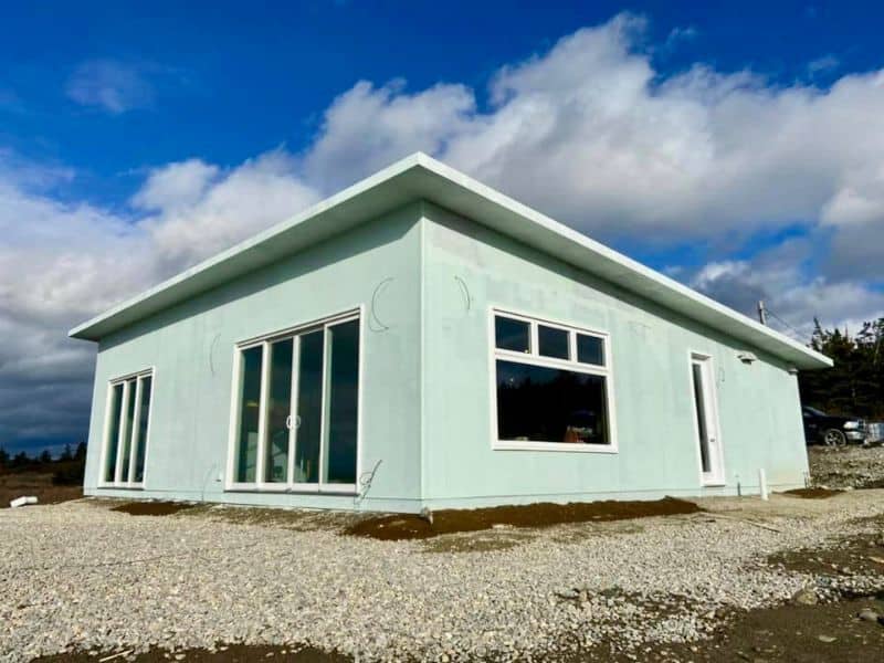 A photograph of the Sandford Home made from over 630 thousand water bottles. It is a single story home with large windows and light green walls. The image shows it still under construction so the finishings still need to be done but the roof and wall are complete.