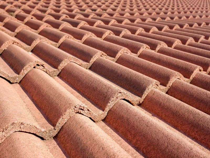 Red-brown terracotta tiles on a roof, laid in an overlapping pattern to allow rain to run off.