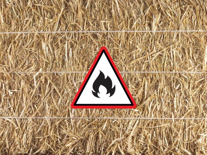 A straw bale held together with three lengths of twine. There is a fire warning sign on top.