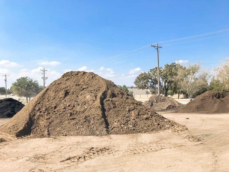 Piles of soil ready for use in a rammed earth building project.