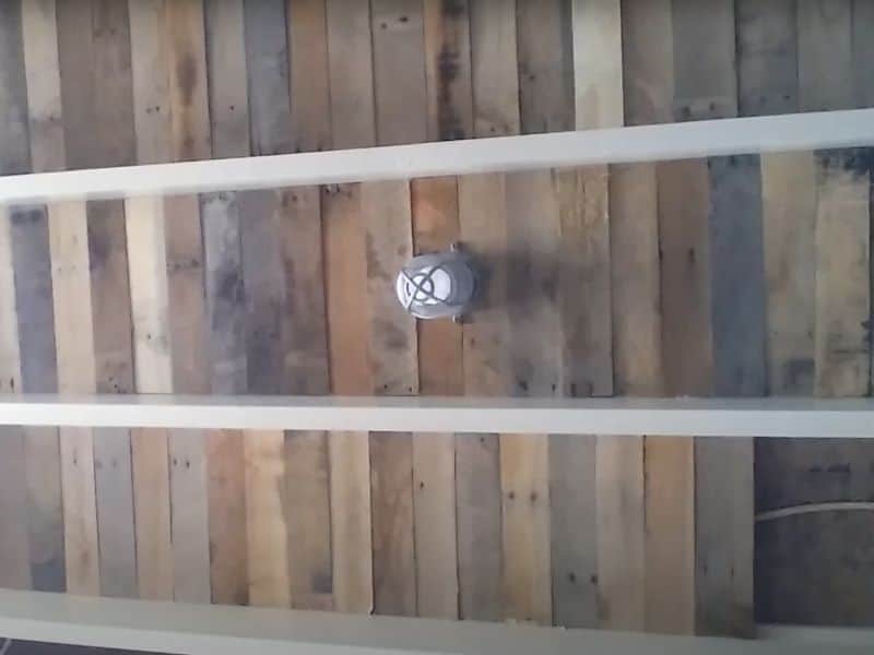 A YouTube screenshot from a video explaining how to install a reclaimed wood ceiling. The image shows the almost finished ceiling with the light fitting reattached.