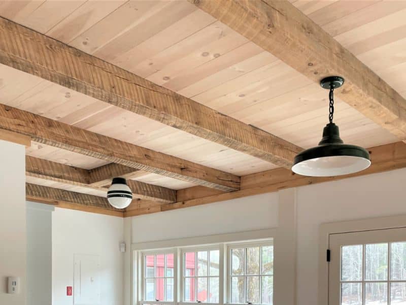 Reclaimed wood beams against wood paneling in a reclaimed wood ceiling. The saw marks are clearly visible in the beams and the grain patterns of the beams and panels add character.