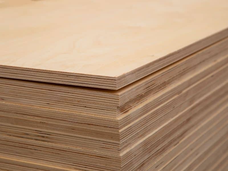 Sheets of light brown plywood stacked neatly on top of each other. The corners of the boards are pointed towards the camera, and the individual layers of wood used in their manufacture are visible in the cross-sections of the boards.