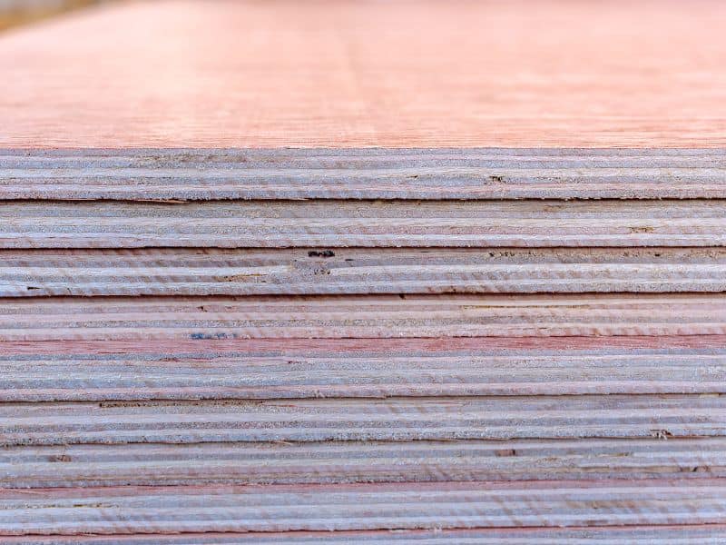 Plywood sheets neatly stacked on top of each other. The photo is taken from the side and the individual layers in each sheet are clearly visible.