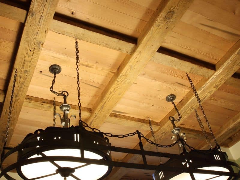 A reclaimed Douglas fir ceiling with square-framed beams and wooden paneling. Heavy-duty metal-framed lighting hangs from the ceiling by chains.