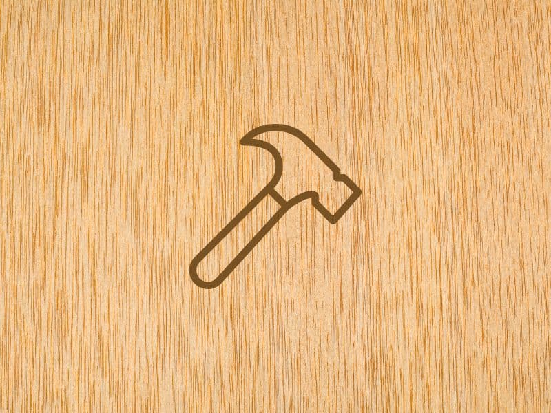 The top surface of a sheet of plywood with the outline of a claw hammer drawn on top of it. The grain runs vertically from top to bottom.