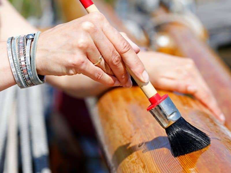 A person applying water-white sealer to a piece of reclaimed wood.