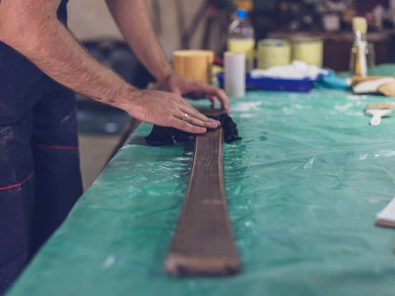 A carpenter cleans a piece of reclaimed wood with a lint-free cloth.