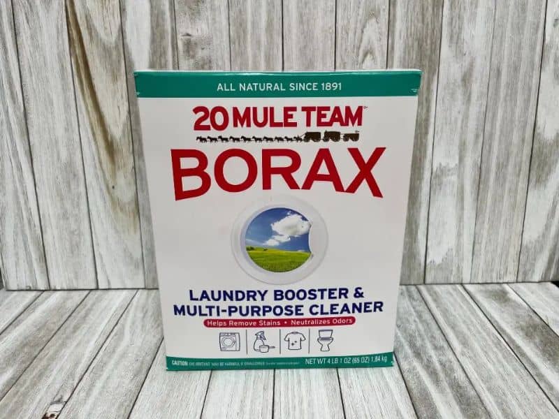 A cardboard packet of borax sitting on a wooden shelf.