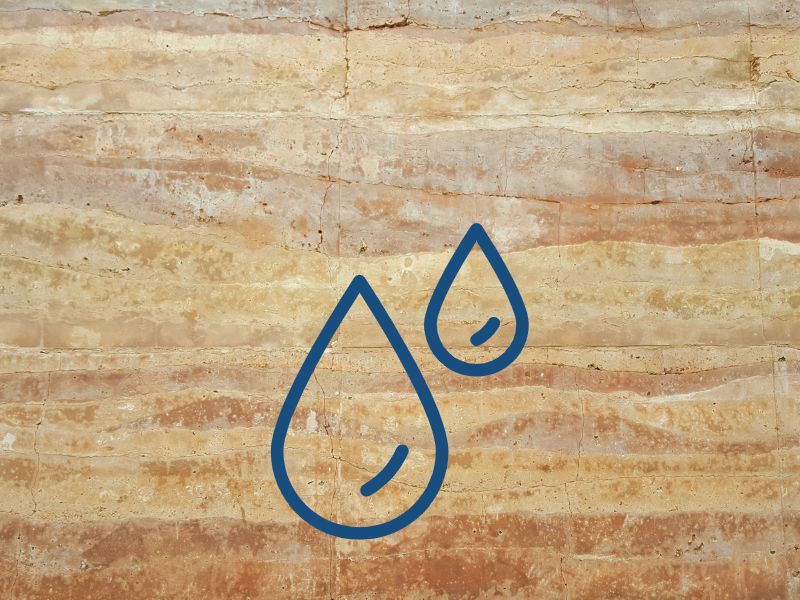 A photograph of a rammed earth wall with layers of soil visible. Overlain is a cartoon image of two droplets of water. 