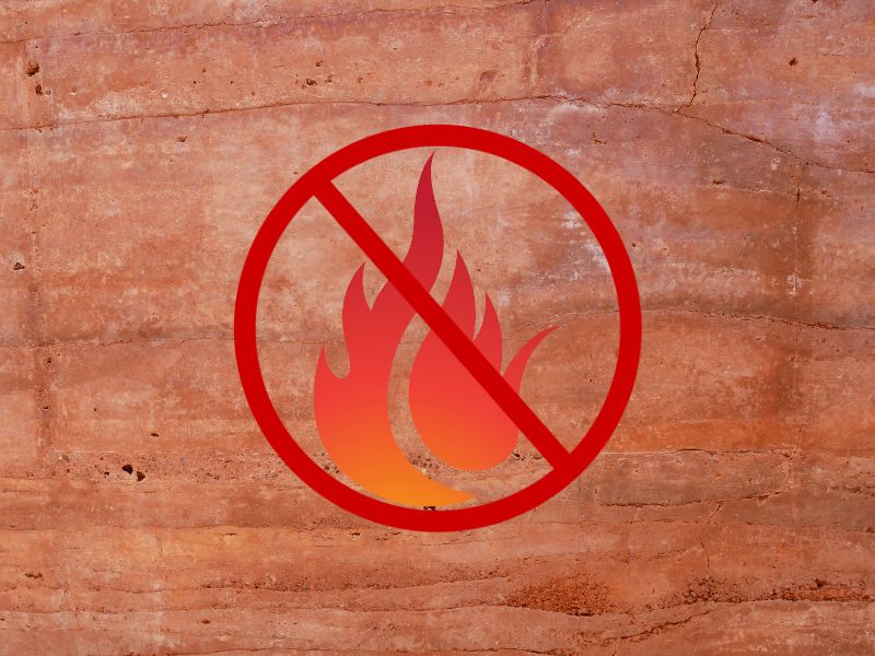 A rammed earth wall with a fire graphic and a red circle with a diagonal line across it.