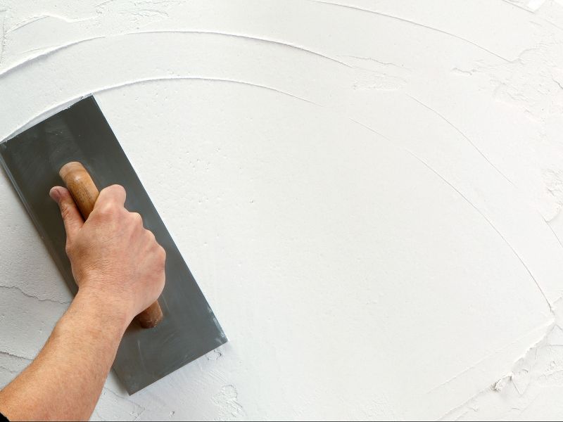 Lime plaster is applied to a cob wall using a hand-held float.