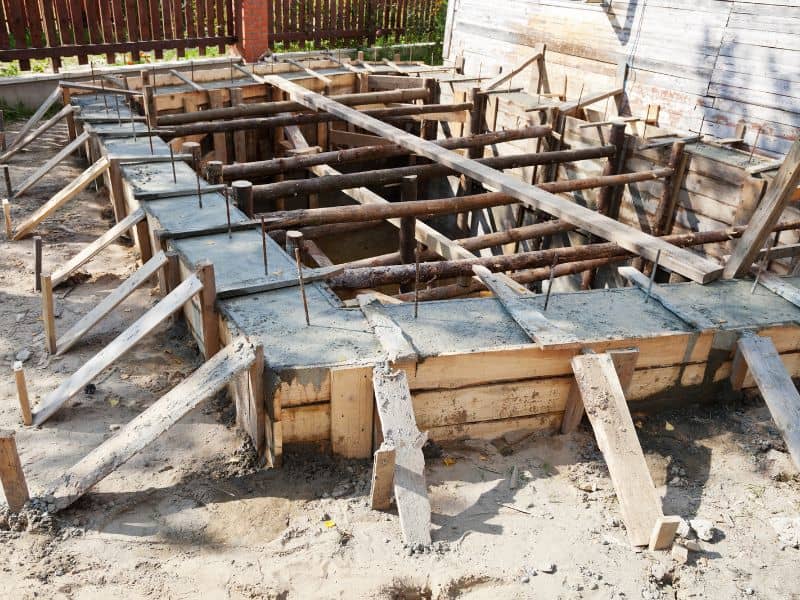 A foundation for a cob house comprising wooden forms with concrete poured in and rebar sticking out of the top.