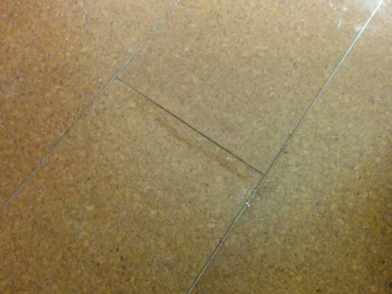 A water-damaged cork floor with ugly discoloration and slight warping, causing the floor to become warped.