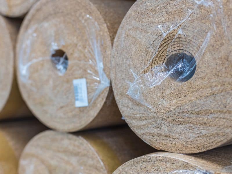 Rolls of cork insulation stacked in neat rows. Individual rolls are wrapped in plastic.