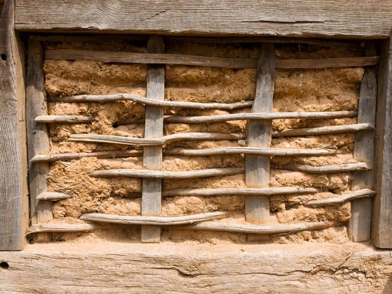 A wattle and daub wall with the wood and mud clearly visible.