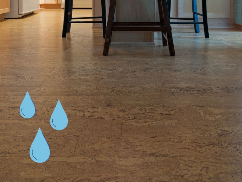 A cork floor in a kitchen with chairs and a table. Cartoon water droplets are overlain in the left hand bottom corner.