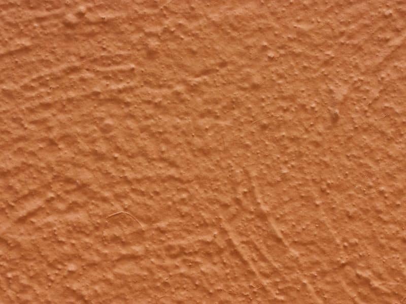 A closeup photograph of an orange stuccoed wall.