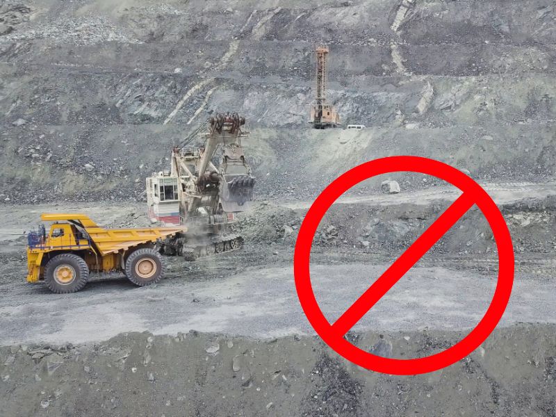 An opencast iron ore mine with large machinery digging out the ore. In the bottom right of the image is a red circle with a diagonal line through it.