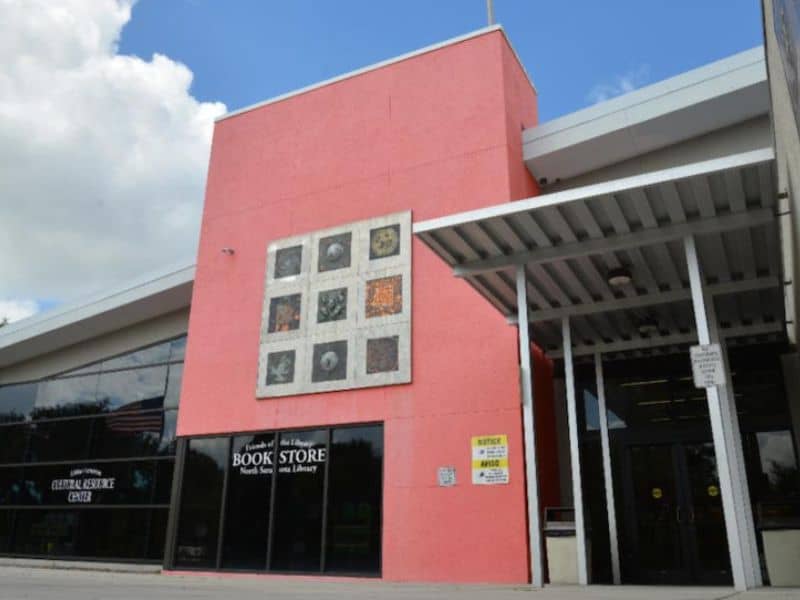 A photograph of the Betty J. Johnson North Sarasota Library. The building has an irregular-shaped pink façade.