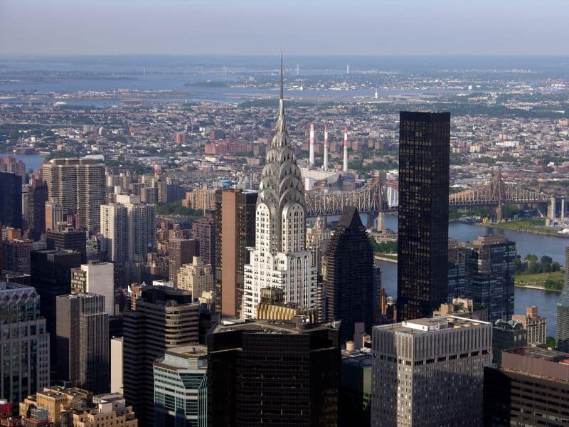 A photograph of the Chrysler Building with its tall spire rising higher than the surrounding skyscrapers on the New York skyline.