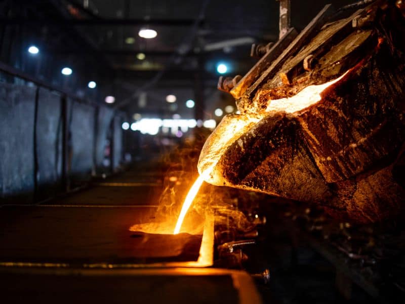 Molten steel is poured from a ladle at a steel foundry into molds where the metal will solidify and cool.