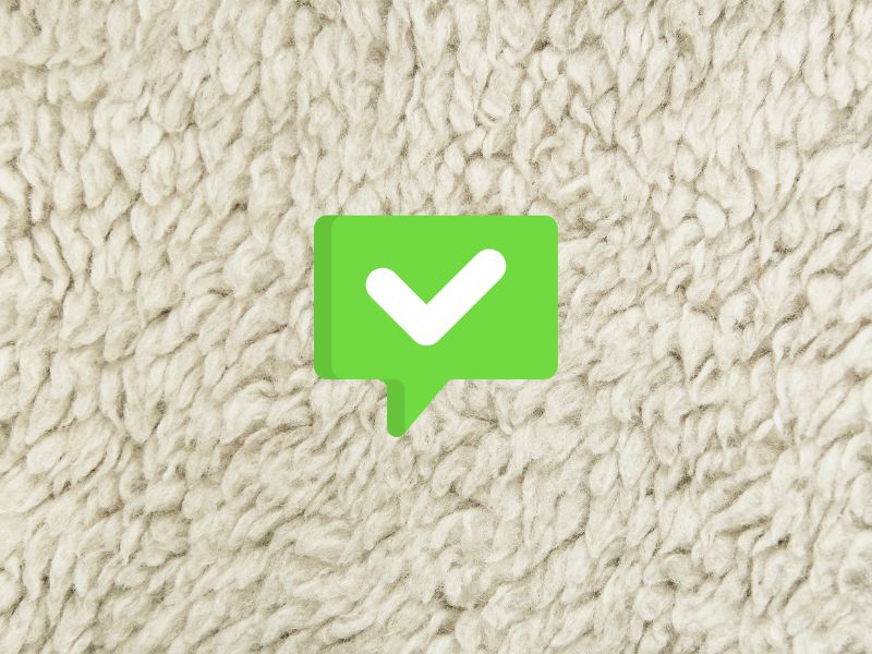 A white sheep's fleece with cartoon green tick speech bubble overlain to indicate the concept of the pros of sheep's wool insulation.