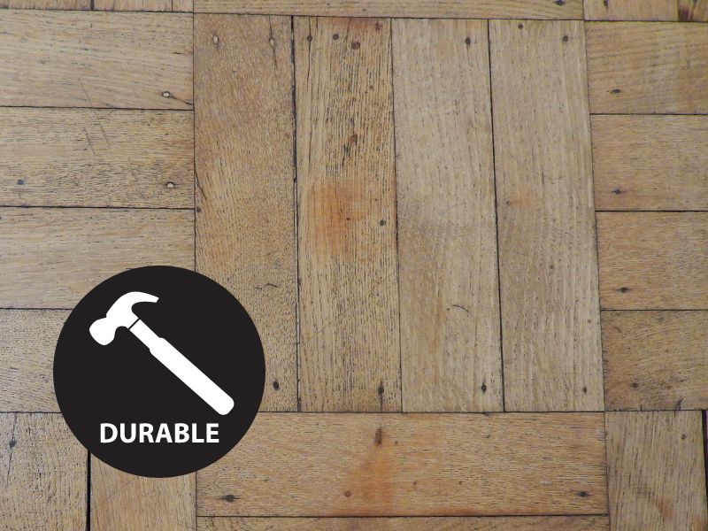 A reclaimed wood floor with a "durable" symbol in the bottom left corner, which comprises a black circle with a white hammer and white writing that says, "durable."