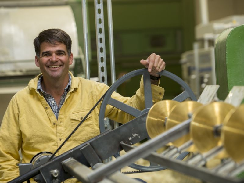 A photograph of Andrew Legge of Havelock Wool standing behind a wool processing machine at Havelock Wool's factory in Reno, Nevada.