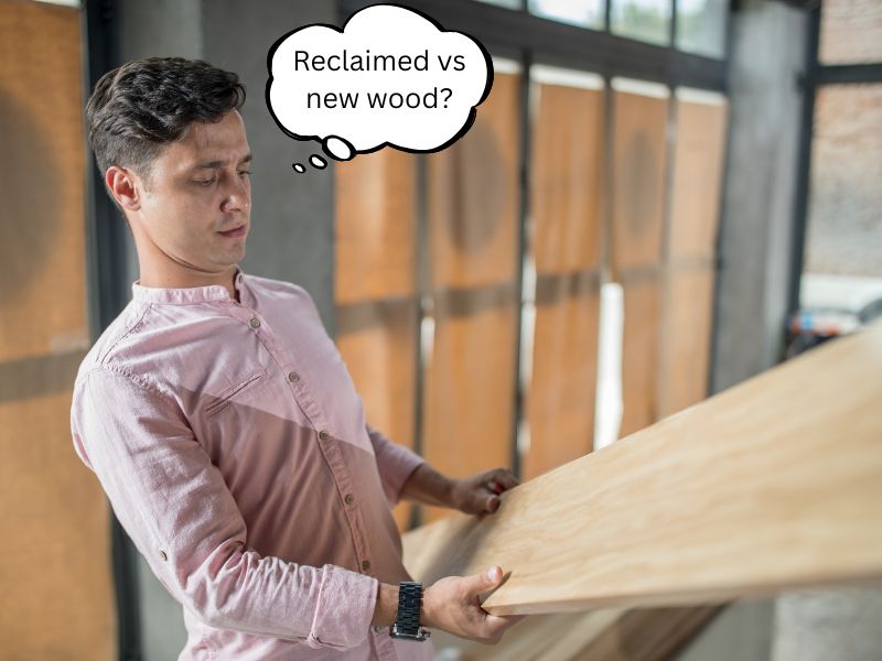 A photograph of a man assessing a plank of wood. He has a thought bubble coming from his head containing the words, "Reclaimed wood vs new wood?"